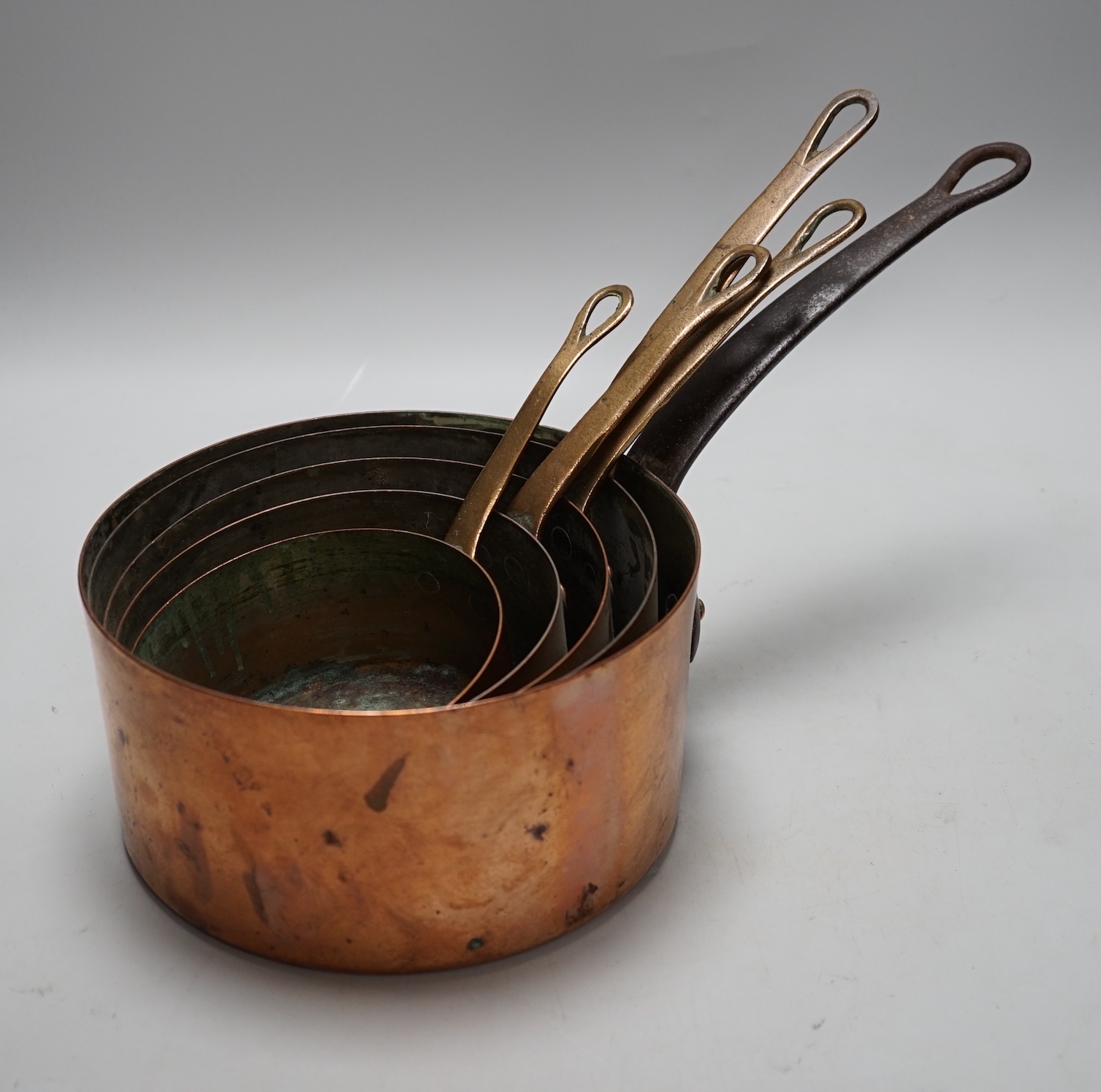 A quantity of various copper-ware including graduated pans, lidded cauldron and miniature warming pans, largest 39cm wide